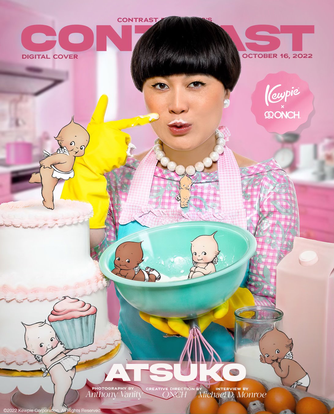 Comedian and HBO Max star Atsuko Okastuko poses on the cover of contrast Magazine wearing a pink and teal 1950s style dress paired with a pink and teal kitchen apron and yellow cleaning gloves. The image features 5 illustrated Kewpie doll characters representing different skin tones. This editorial was produced by ONCH, formerly known as Onch Movement. Atsuko is also wearing a Kewpie necklace designed by ONCH.