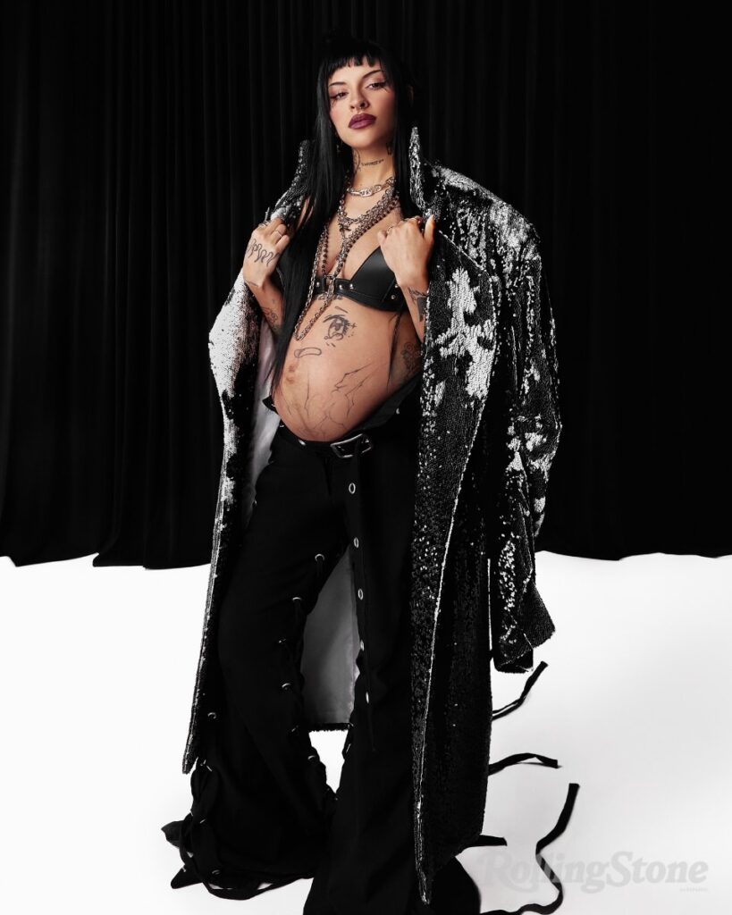 Cazzu posing pregnant for Rolling Stone en Espanol. Fashion credits include: Vestido de microtul @KlappenOficial; Maxi botas Ricky Sarkany; Guantes y anillos de plata, Limido.; Cadenas Aracano Jewelry; Cadena con dije, Panker